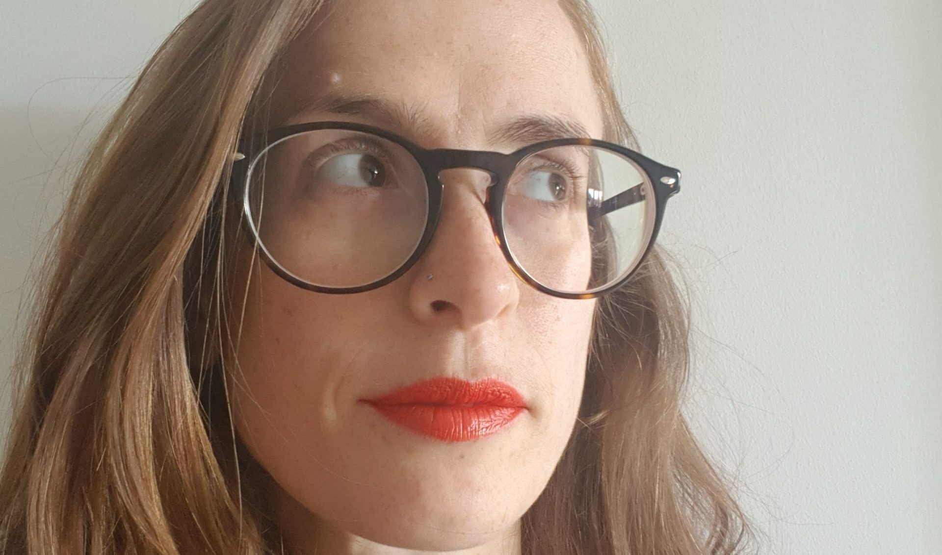 a person with long hair, red lipstick and glasses looking up