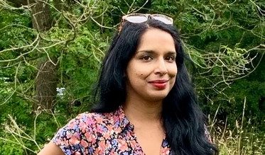 a woman with long black hair standing in a field