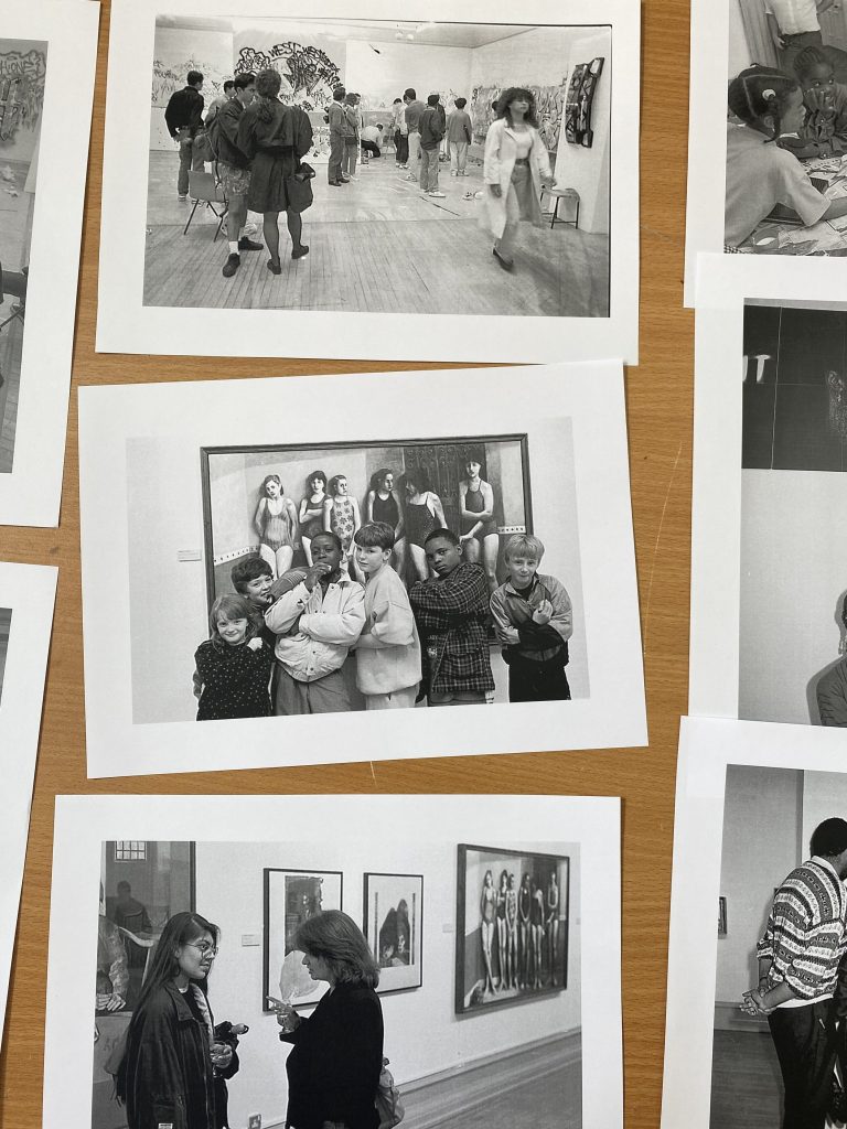 a photo of three black and white photos of people chatting and interacting in an art gallery 