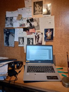 an image of a laptop in front of a wall with lots of notices pinned