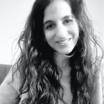 a black and white photo of Aliya Gulamani, a woman with long dark wavy hair 