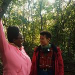 a picture of two people of colour smiling in a forest