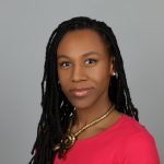 a person wearing a bright pink top and long black braids looking at the camera with a slight smile