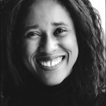 a black and white photo of a woman with long dark hair smiling at the camera