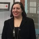 a woman wearing a black blazer and smiling at the camera 