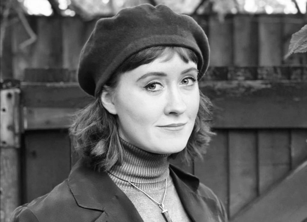 a woman in a beret with shoulder-length hair smiling