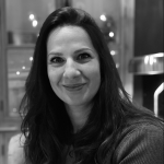 A black and white photo of a woman smiling, with long dark hair.