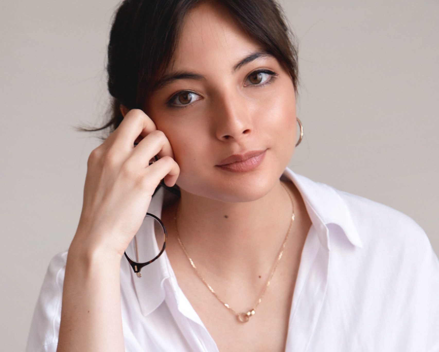 Image of Cecile Pin, a woman who smiles and sits relaxed with her hand rested on her crossed leg. She wears a white shirt and blue jeans. She has dark hair pulled up in a ponytail.