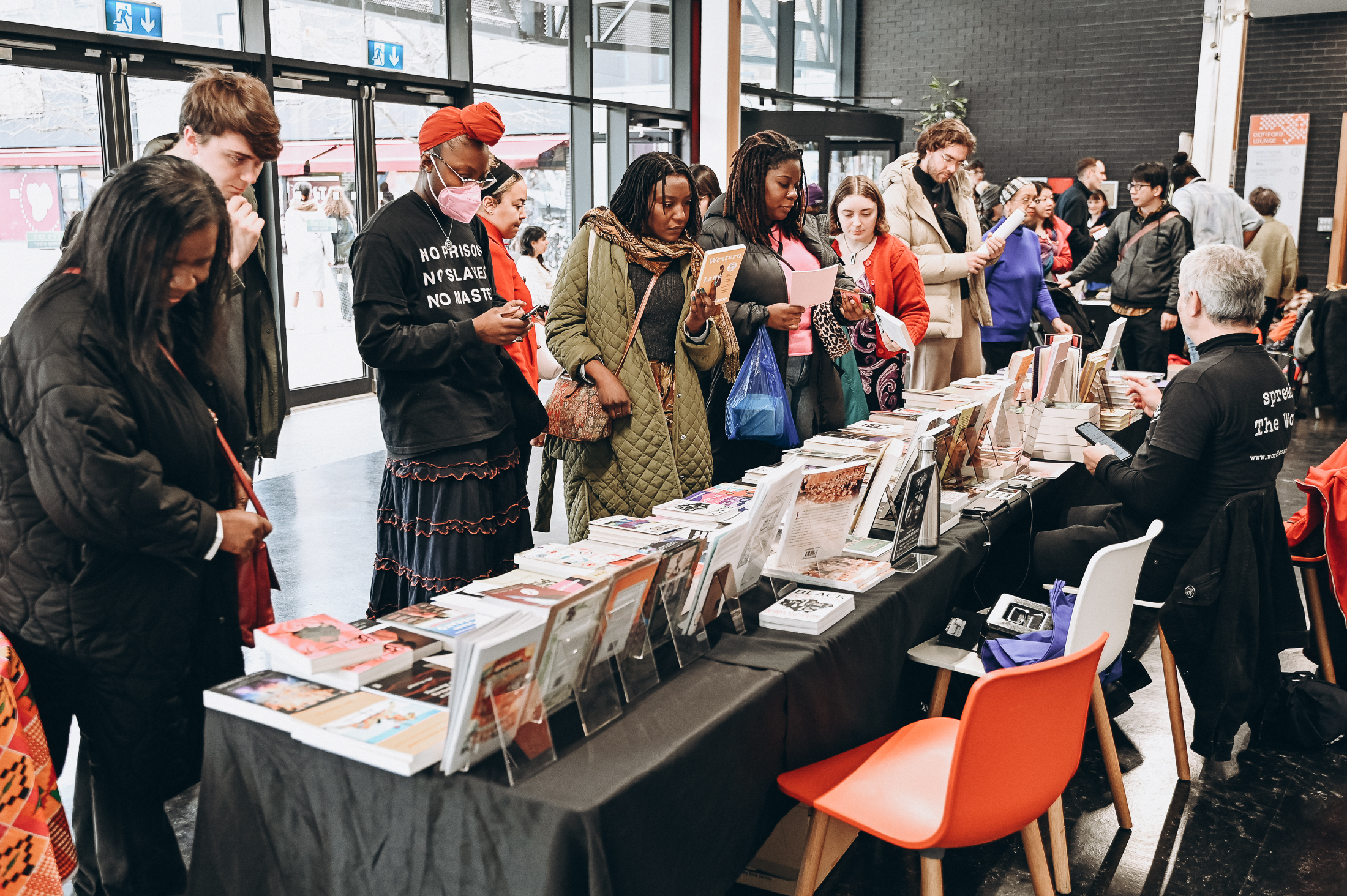 Photograph of people at a bookstall, looking at and picking up books.